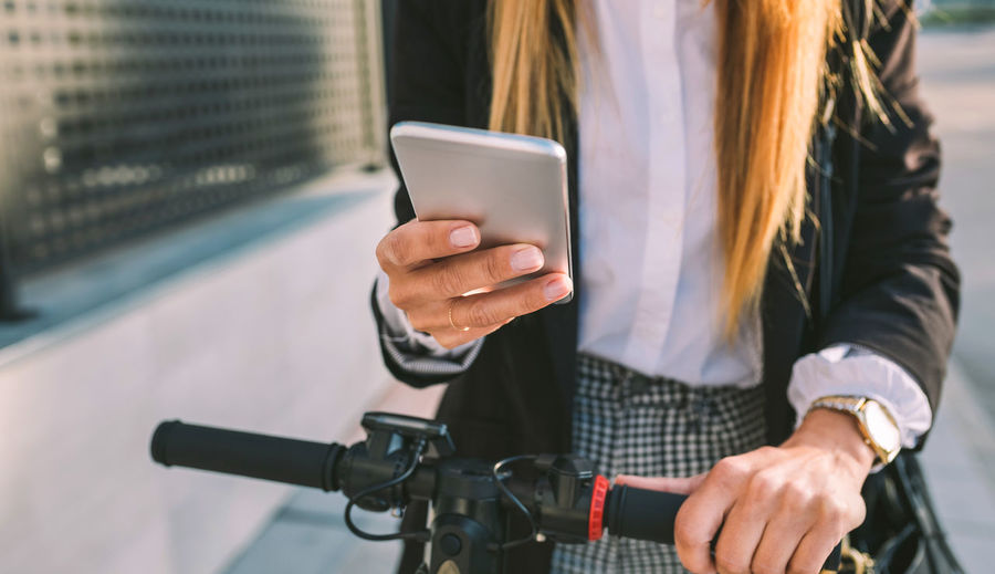 Midsection of woman using mobile phone in city