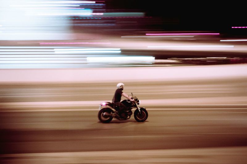 Blurred motion of man riding motorcycle on road at night