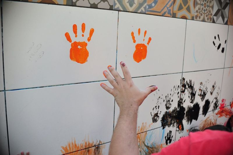 Cropped image of man with handprint on tile wall