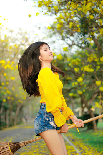 Beautiful young woman standing against yellow leaves