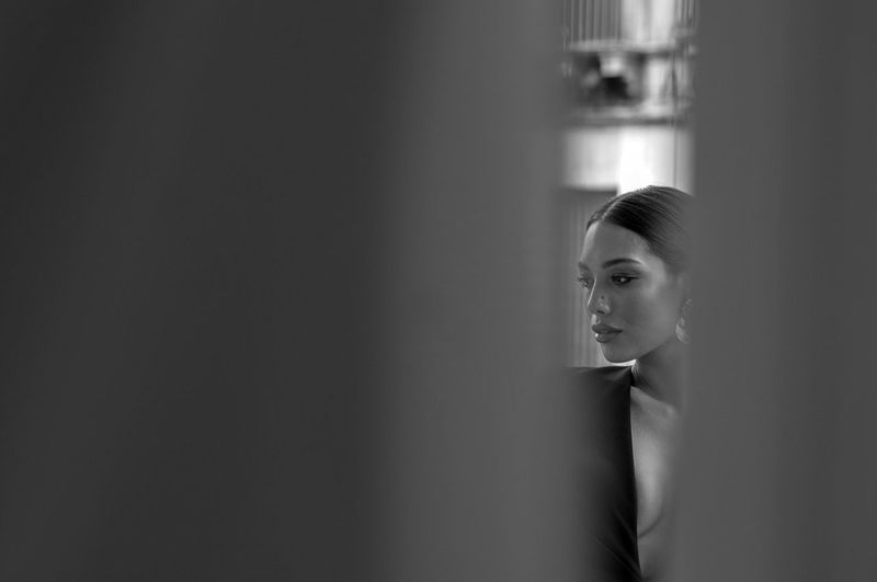 Portrait of young woman looking away against wall