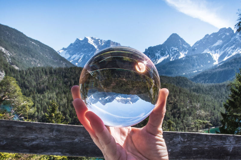 Human hand holding glass with mountain in background