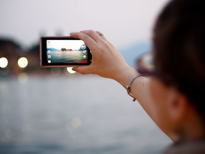Close-up of woman photographing with mobile phone by lake