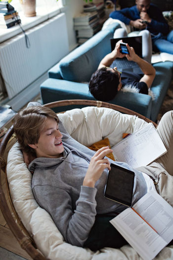 High angle view of friends using social media while studying in living room