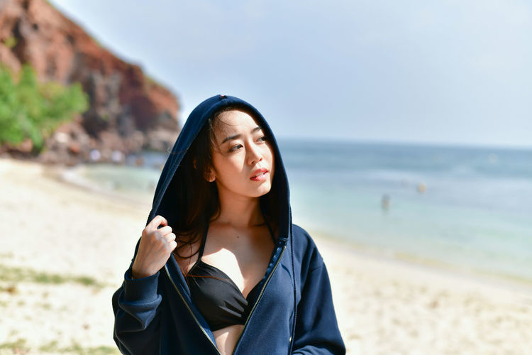 Young woman looking away while standing at beach