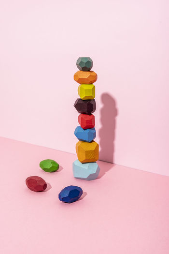 Multi colored wooden blocks stack against pink background