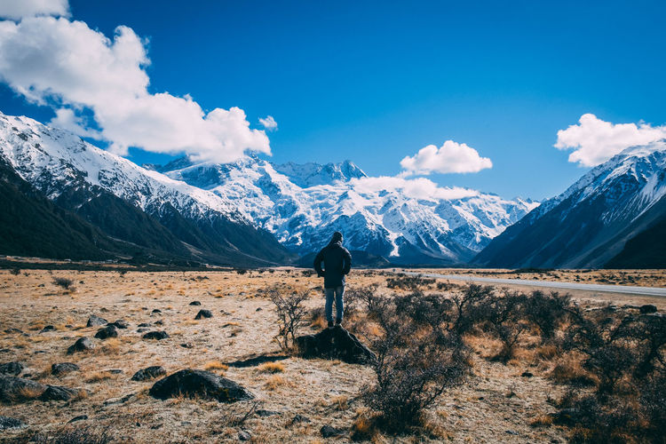 Man standing on field against snowcapped mountains