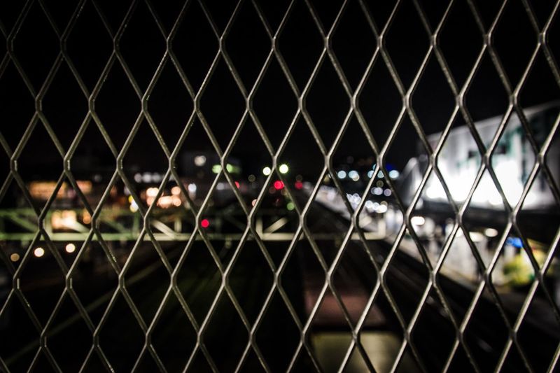 View of street seen through chainlink fence at night