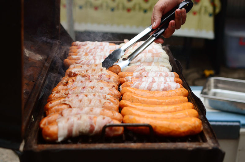 Close-up of person preparing meat on barbecue grill