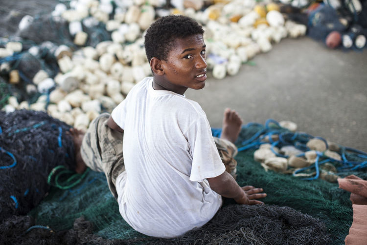 Portrait of teenage boy sitting on fishing net
