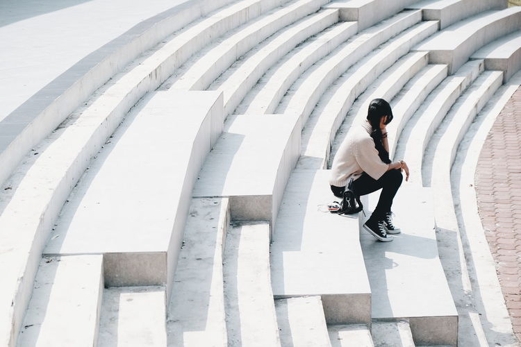 HIGH ANGLE VIEW OF WOMAN SITTING ON FLOORING