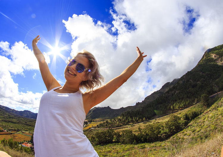 Happy woman with arms raised against sky