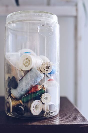 Close-up of glass jar contains sewing threads 