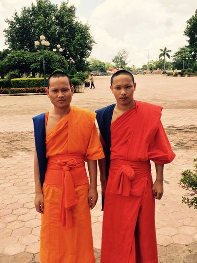 Portrait of monks standing on paved footpath