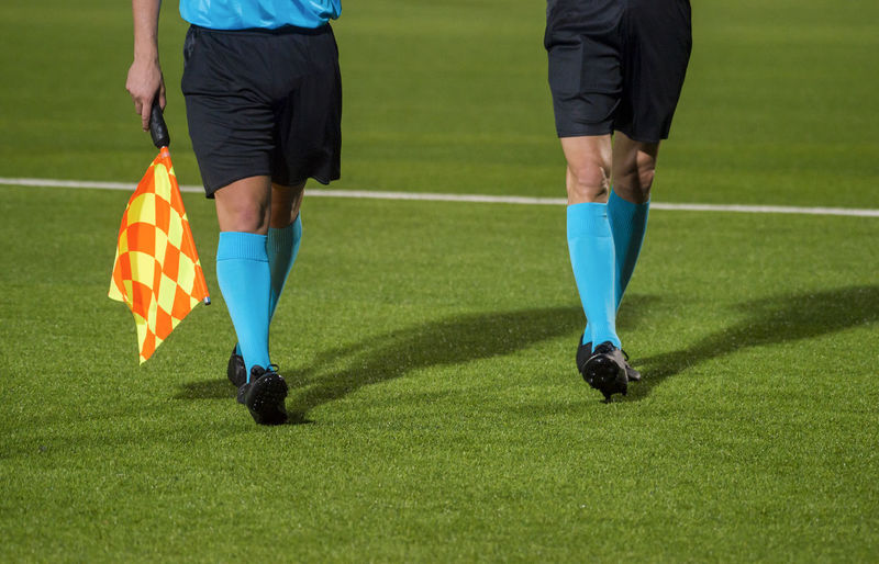 Low section of referees walking on soccer field
