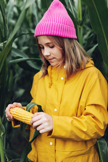 Funny little girl dressed in a yellow raincoat and a hot pink cap spoils