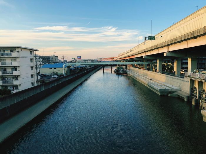 Bridge over river amidst buildings in city against sky