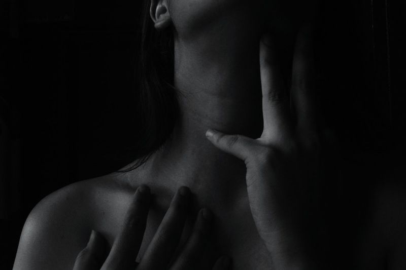 Midsection of topless woman against black background
