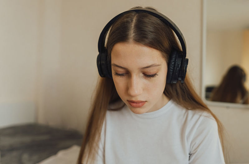 Portert a generation z teenager girl in headphones, sadly looks down.