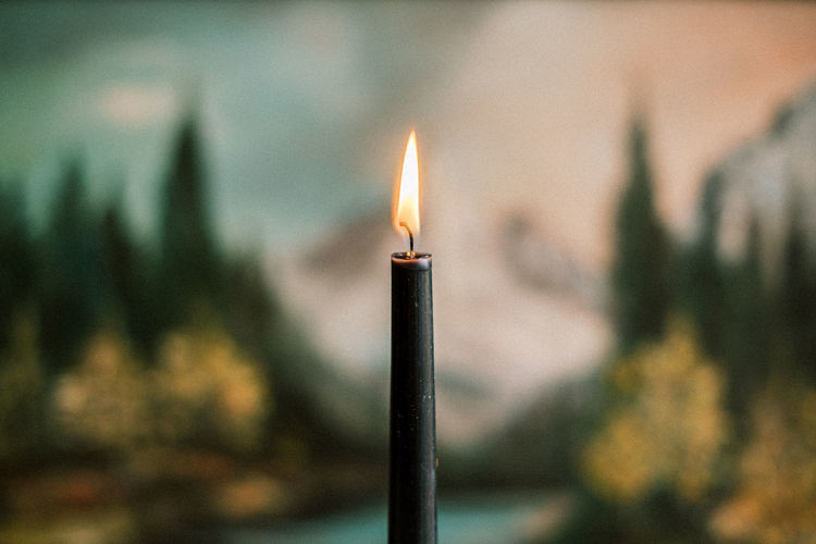 Close-up of a burning candle against the backdrop of a painting for a warm and moody vibe.