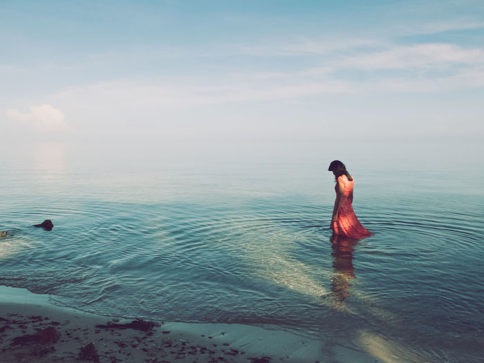 Woman standing at shore against sky