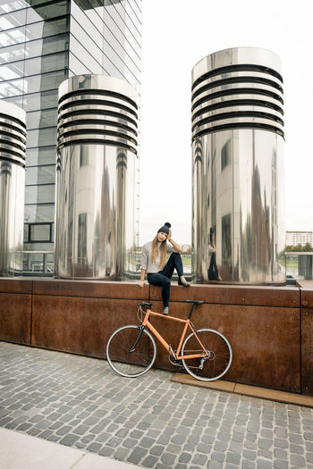 Young woman with bicycle having a break in the city