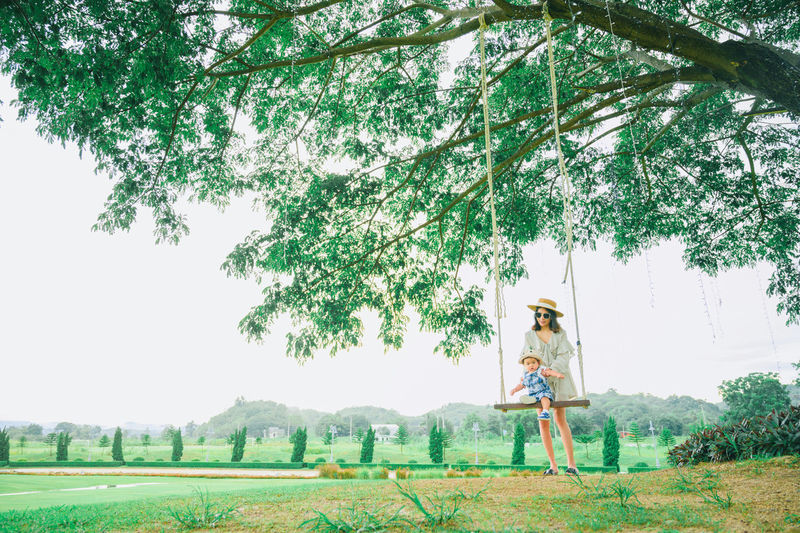 Woman on field by trees against sky