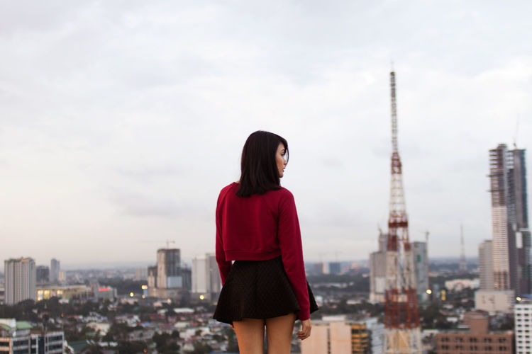 Woman standing in front of cityscape against sky