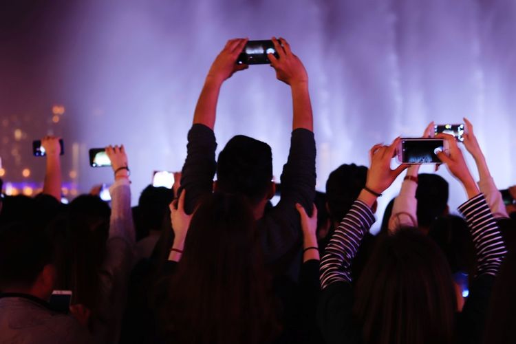 Group of people photographing at music concert during night