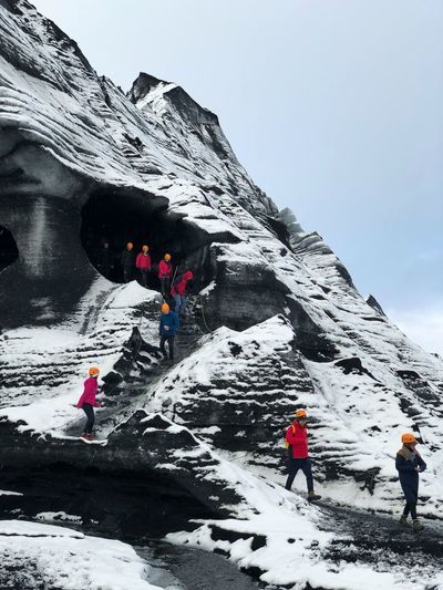People walking on snowcapped mountain against sky
