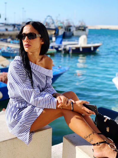 Woman wearing sunglasses sitting against sea