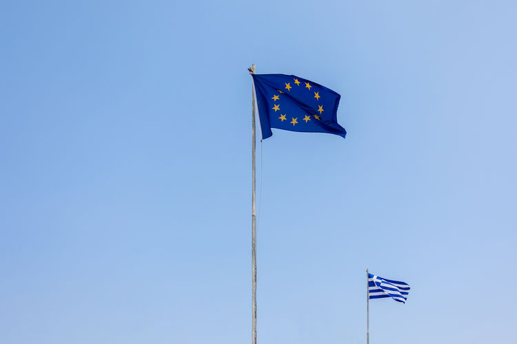 European union eu and greece flags is flying in air on blue sky background. banner, place for text
