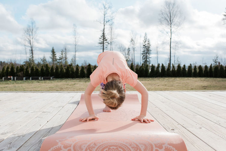 Young girl doing yoga outside in her back yard at home