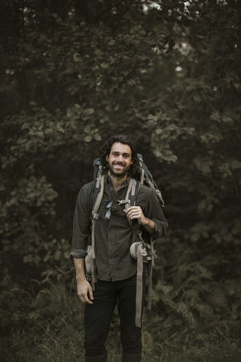 Portrait of smiling man with backpack in forest