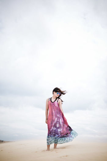 Silhouette of woman standing against cloudy sky at the beach