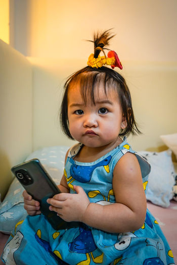 Portrait of cute girl using mobile phone at home