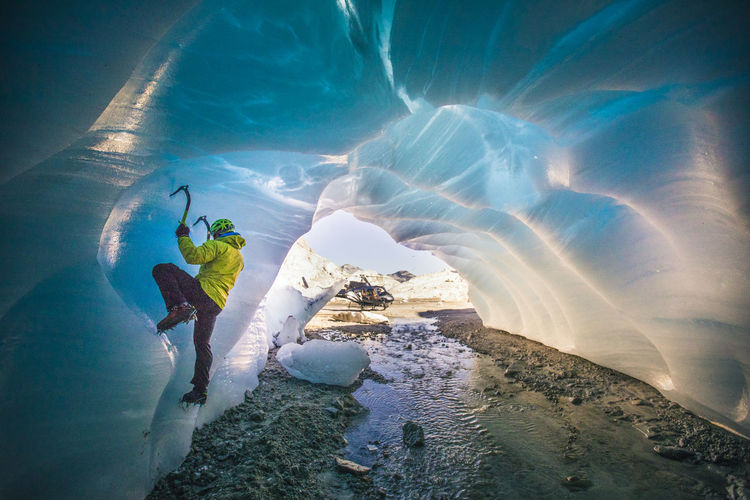 Man ice climbing in cave during luxury adventure tour.