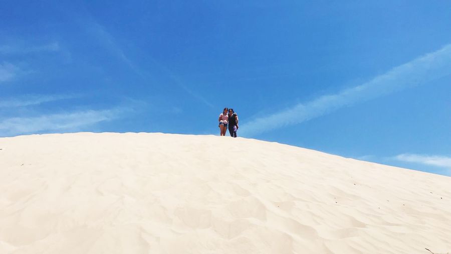 Low angle view of teenage girl standing with mother at desert on sunny day
