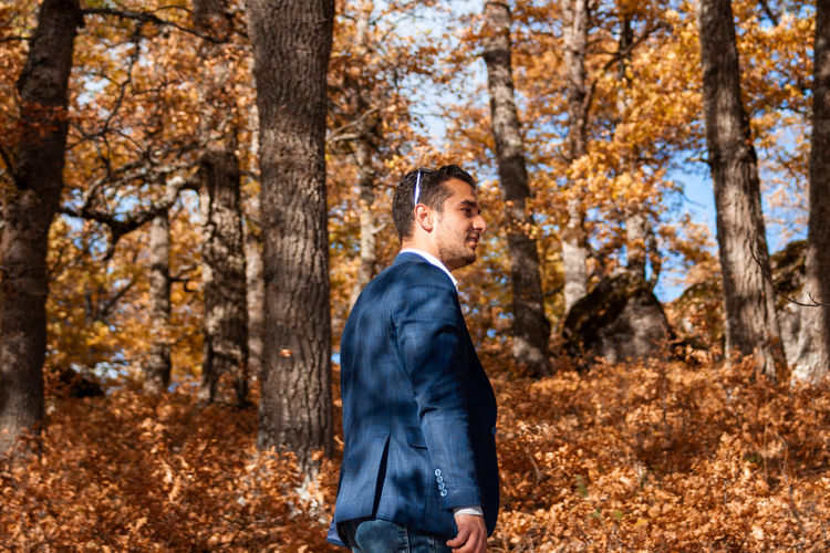 Man standing by tree trunk in forest during autumn
