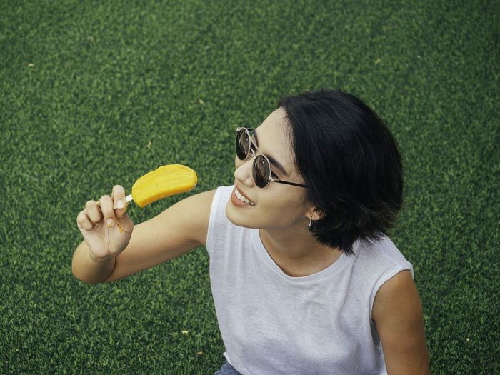Portrait of woman holding sunglasses on grass
