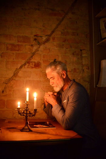 Man holding lit candle in the dark
