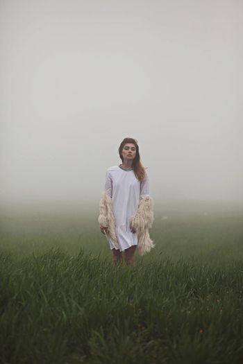 Portrait of young woman standing in grass