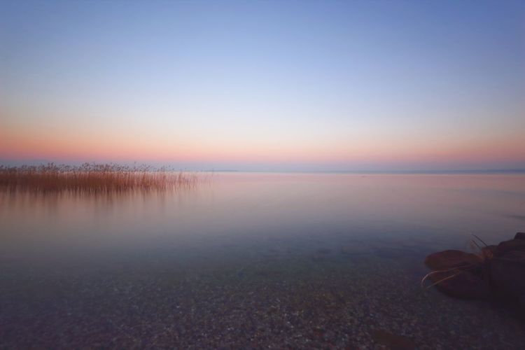 Scenic view of lake against clear sky at sunset