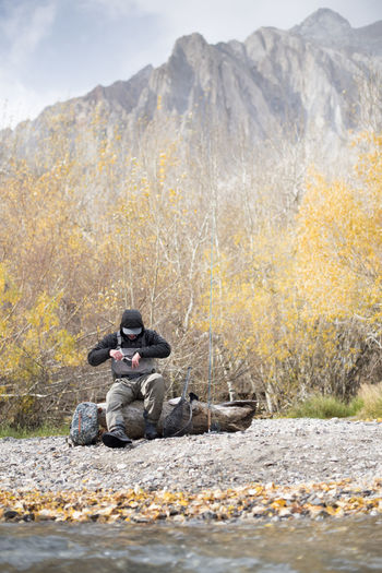 A fly fisherman prepares his gear in a beautiful mountain setting.