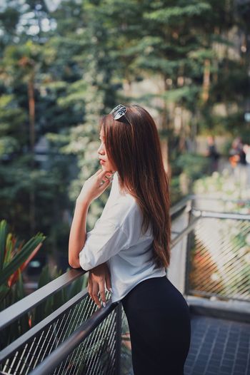 Side view of woman standing by railing