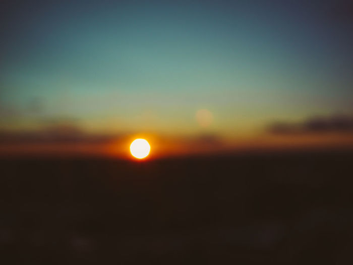 Defocused image of landscape against sky during sunset