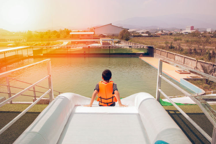 Rear view of boy sitting on water slide