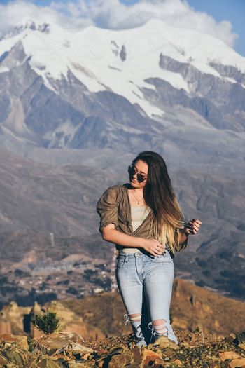 Full length of young woman standing on landscape against mountains