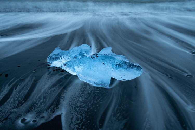 Close-up of blue iceberg washed up on black sand beach in iceland