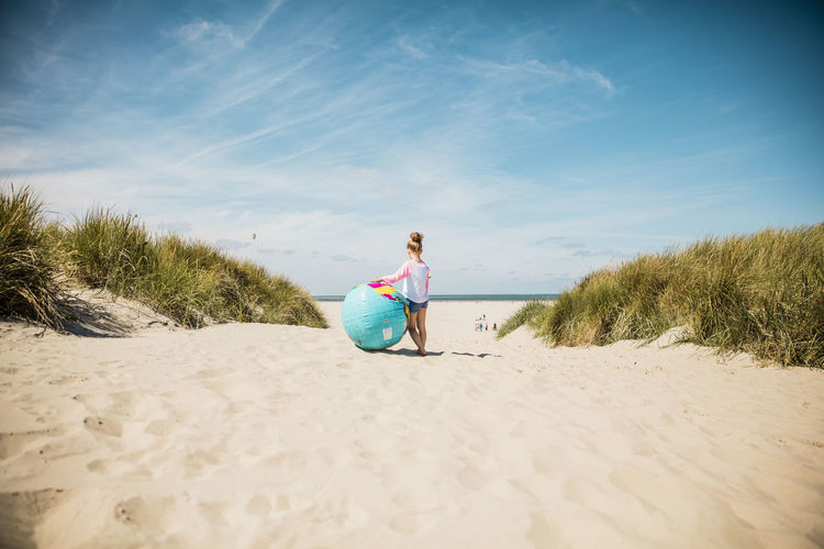 Girl with globe on the beach